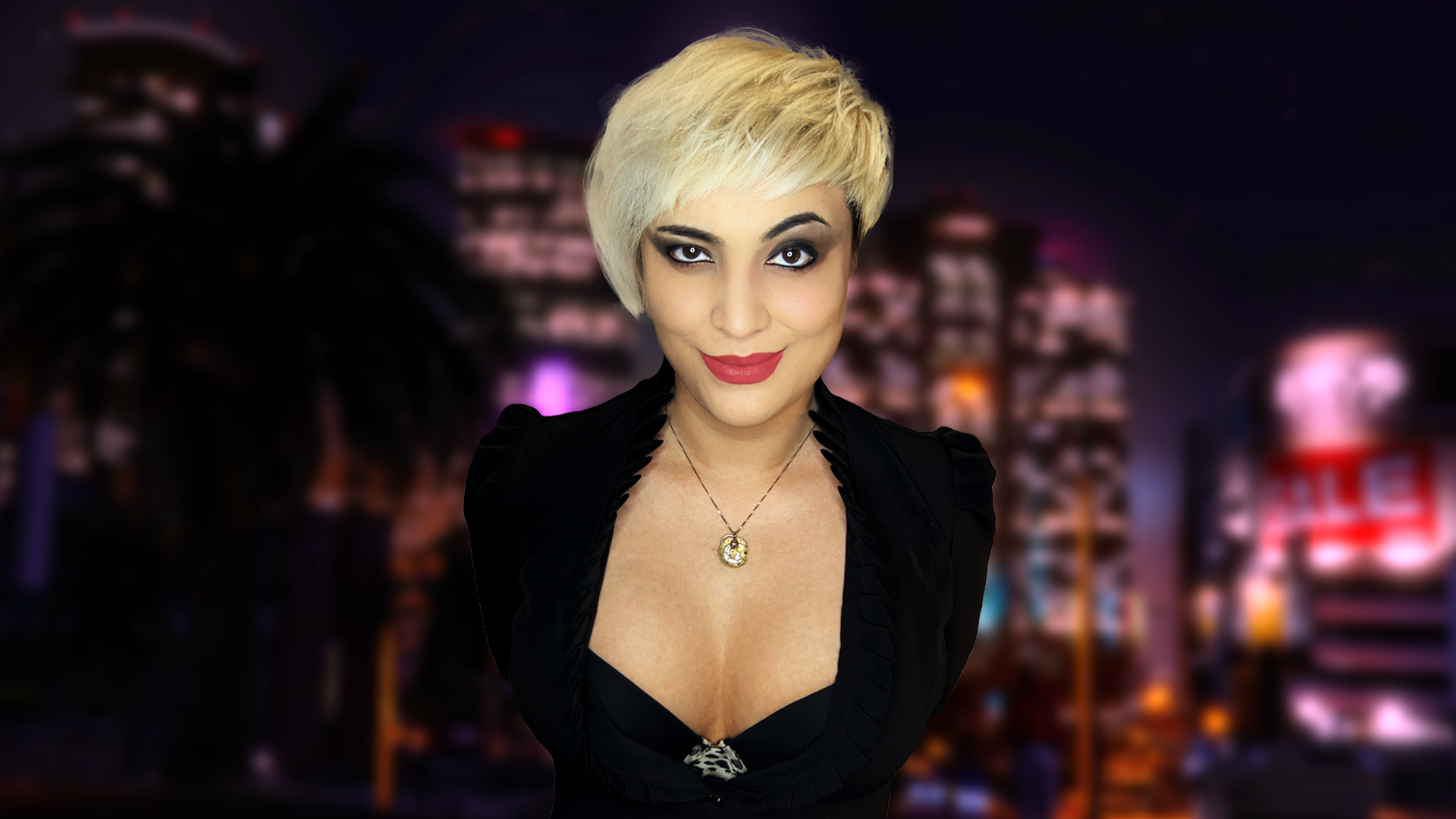 A mid-30's latina with a wolf cut hair style faces the camera. She's dressed in black shirt, a waistcoat, a belt buckle, and she has a hankerchief around her neck. She has tattoos on her right arm.